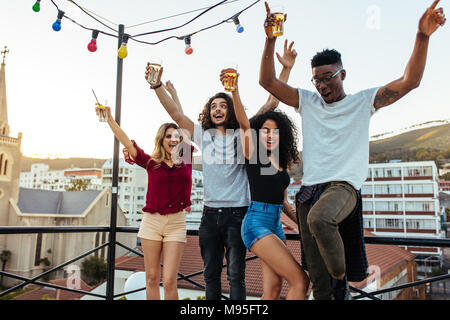 Junge Leute feiern auf der Terrasse bei einem Drink. Gemischten rennen Männer und Frauen einen Drink auf der Dachterrasse. Stockfoto