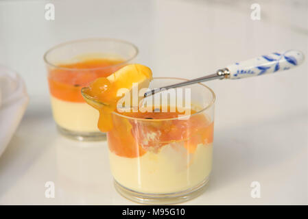 Panna cotta mango Nachtisch mit Löffel auf weißem Marmor Stockfoto