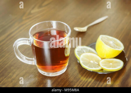 Auf der Oberfläche des Tisches in einem Glas Tasse heißen starken Tee und Zitrone. Stockfoto