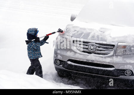 Ein Junge (5 Jahre alt) Bürsten frisch gefallenen Schnee von einem Auto in Quebec, Kanada Stockfoto