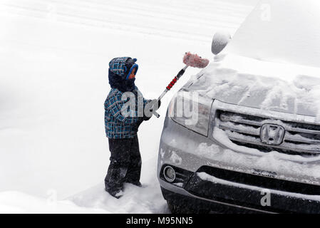 Ein Junge (5 Jahre alt) Bürsten frisch gefallenen Schnee von einem Auto in Quebec, Kanada Stockfoto