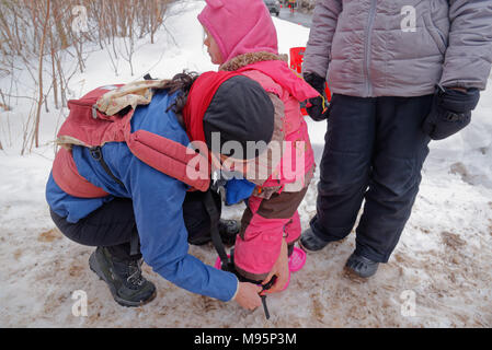 Eine Mutter tun, bis die Schneeschuhe auf ein kleines Mädchen (3 Jahre alt) im kanadischen Quebec Stockfoto