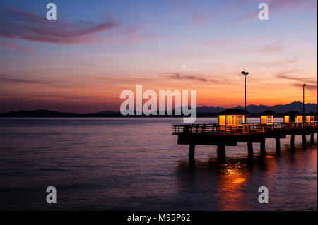 Angelpier an der Elliott Bay mit Halbmond und Olympic Mountains mit dramatischem Sonnenuntergang Stockfoto