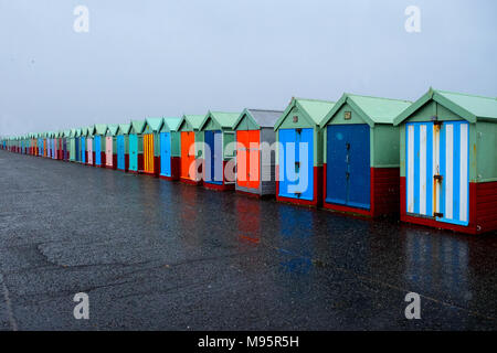 Eine Linie von 40 Strandhütten mit verschiedenen bunten Türen auf eine konkrete Promenade, der nächste Strand Hütten auf der rechten Seite des Bildes sind groß, t Stockfoto