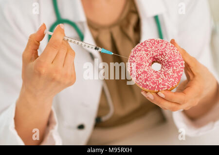 Closeup auf Arzt Frau macht Injektion mittels Spritze Diabetes in donut Stockfoto