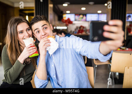 Glückliches Paar essen Burger und Döner selfie gemeinsam in Fast food Stockfoto