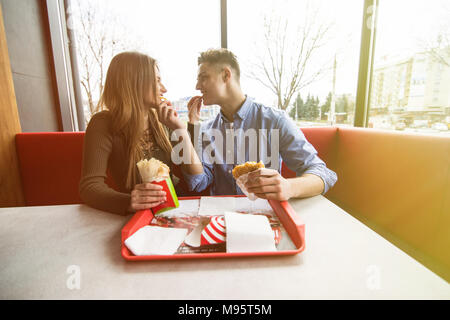 Paar in Liebe umarmen Spaß, zusammen mit einem Lächeln. Schöner Freund Witz ihrer Freundin und ihren Feed, Pommes frites. Stockfoto