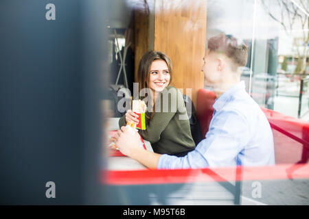 Paar in Liebe umarmen Spaß, zusammen mit einem Lächeln. Schöner Freund Witz ihrer Freundin und ihren Feed, Pommes frites. Stockfoto