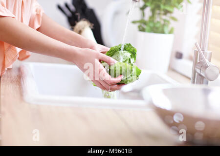 Junge Frau Waschen von Salat in der modernen Küche Stockfoto