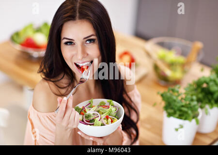 Glückliche Frau Zubereitung Salat in der modernen Küche Stockfoto