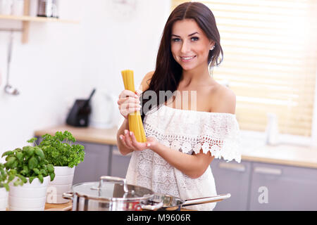 Junge Frau, die versucht, Pasta in der Küche vorbereiten Stockfoto