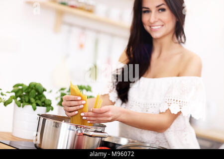 Junge Frau, die versucht, Pasta in der Küche vorbereiten Stockfoto