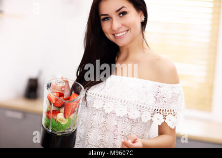 Freundlich lächelnden jungen Frau Vorbereitung gesunde Smoothie in der modernen Küche Stockfoto