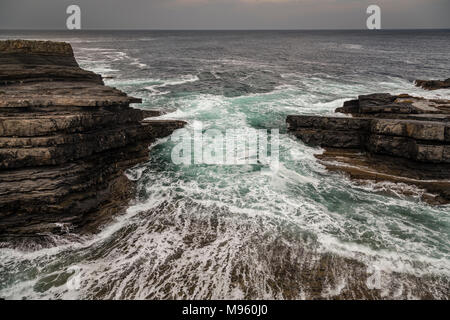 Wellen gegen Felsen am Loop Head Brücken von Ross an der Ostküste Irlands in der Grafschaft Clare Stockfoto