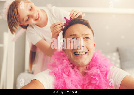 Happy netter Mann trägt einen rosa Feder Boa Stockfoto