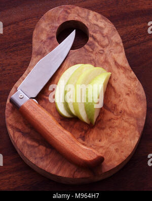 Schneiden Sie in Scheiben geschnitten und Apple mit klappbarer Obst Messer auf einem olivenholz Brett. Stockfoto