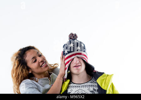 Junge fröhliche Frau, Mütze auf dem Kopf des Menschen Stockfoto