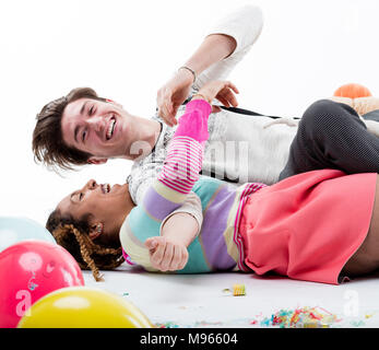 Junge fröhliche Frau Aprilscherze auf dem Boden mit Mann unter party Ballons Stockfoto