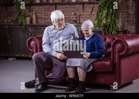 Senior Paar mit Laptop auf der Couch zu Hause sitzen Stockfoto
