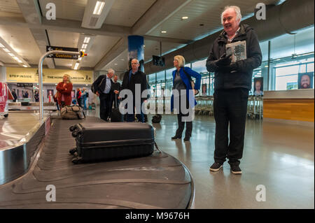 Menschen für ihr Gepäck an der Gepäckausgabe Karussell in Cork Airport, Cork, Irland wartet. Stockfoto