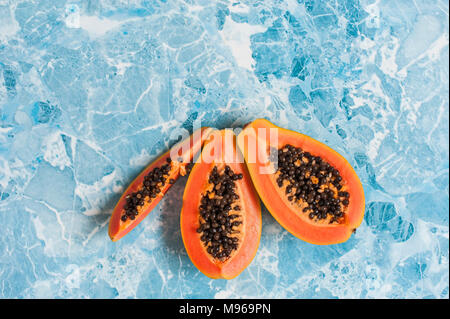 Saftige Scheiben reife Papaya auf blauem Hintergrund. Exotische Früchte, gesundes Essen. Stockfoto