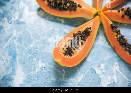Saftige Scheiben reife Papaya auf blauem Hintergrund. Exotische Früchte, gesundes Essen. Stockfoto