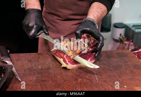Ein Mitarbeiter schneidet Schinken/Marmelade in einem Marmeladenstand, spanischer Schinken im La Mercat de Sant Josep de la Boqueria, Zentrum von barcelona, Spanien Stockfoto