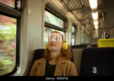 Junge Frau, entspannend, während Auflistung zu Musik Stockfoto