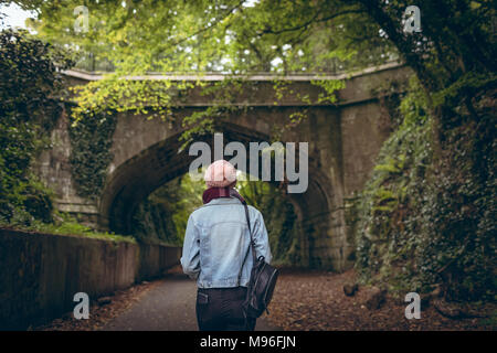 Mädchen in warme Kleidung stehen auf Pfad mit Rucksack im Park Stockfoto