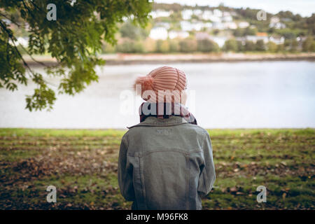 Junge Frau trägt warme Kleidung in der Nähe von Fluss Küste stehend Stockfoto