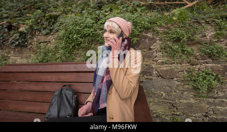 Junge Frau am Telefon sprechen während der Sitzung auf der Werkbank Stockfoto