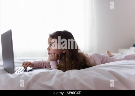 Kleines Mädchen mit Laptop im Schlafzimmer Stockfoto