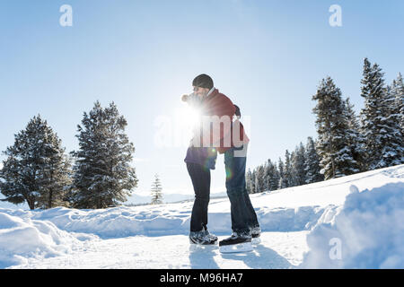 Paar einander umarmen beim Eislauf in verschneiter Landschaft Stockfoto