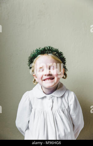 Mädchen lächelnd in weißem Kleid mit Kranz auf dem Kopf Stockfoto