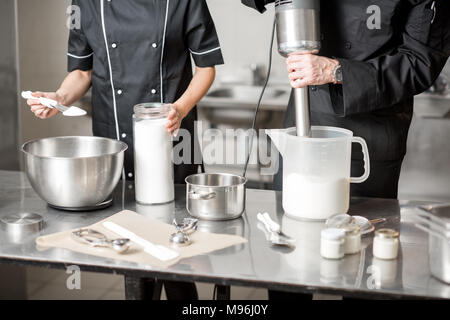 Köche Mischen von Zutaten für Speiseeis Herstellung in der professionellen Küche. Nahaufnahme mit kein Gesicht Stockfoto