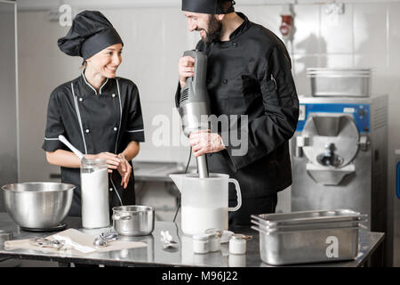 Küchenchef mit junge Frau assistant Eis zusammen Mischen von Zutaten, die in der professionellen Küche des kleinen Fertigung Stockfoto