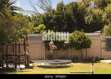 Mädchen springen auf Trampolin im Garten Stockfoto