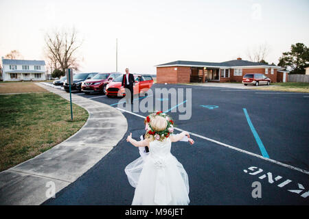 Mädchen in weißem Kleid auf dem Parkplatz mit Blumenkranz Stockfoto