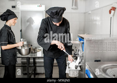 Koch, weißes Eis aus der Eismaschine Maschine in dem kleinen Fertigung Stockfoto