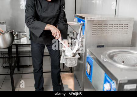 Koch, weißes Eis aus der Eismaschine Maschine in dem kleinen Fertigung Stockfoto