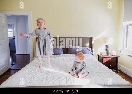 Mädchen und Baby spielt auf dem Bett Stockfoto