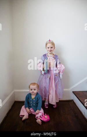 Mädchen in Prinzessin Kostüm neben Baby auf dem Boden Stockfoto