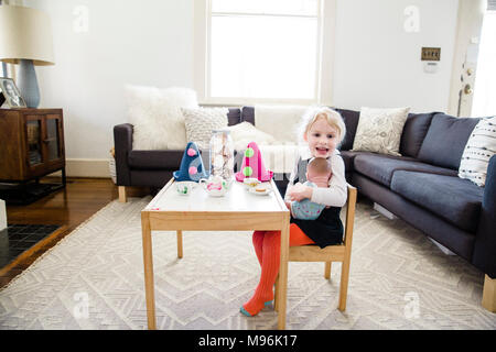 Mädchen sitzen auf Stuhl am Tisch mit Party Hüte auf Stockfoto