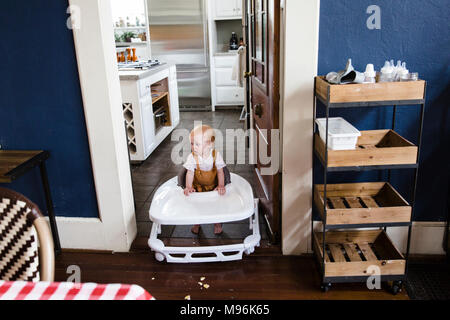 Baby in Walker gehen durch Tür Stockfoto