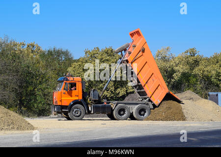 Die Dump Truck entlädt Schutt. Der Stapler gedumpten die Ladung. Sand und Kies. Bau von Straßen. Stockfoto