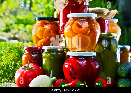 Gläser mit eingelegtem Gemüse und Obst im Garten. Marinierte Lebensmittel. Stockfoto