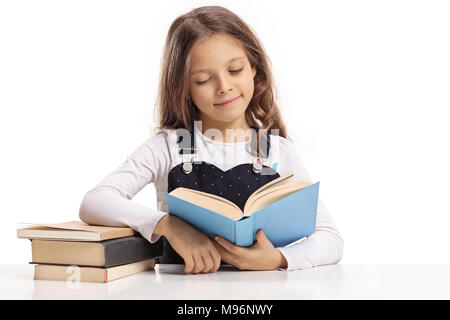 Kleines Mädchen sitzen an einem Tisch und ein Buch auf weißem Hintergrund Stockfoto