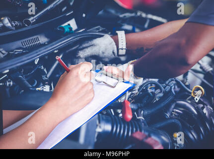 Asiatische Frauen Ingenieure und Techniker prüfen Mechaniker und Inspektion an einem Auto in der Autowerkstatt die Liste auf dem Brett Stockfoto