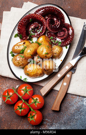 Gegrillter Tintenfisch mit kleinen Kartoffeln mit Kräutern und Gewürzen. Ansicht von oben Stockfoto