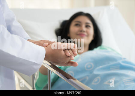 Freundliche mann Arzt Hände halten patient Hand am Schreibtisch für Ermutigung sitzen, Einfühlungsvermögen, Jubel und Unterstützung während der ärztlichen Untersuchung. Gute ne Stockfoto